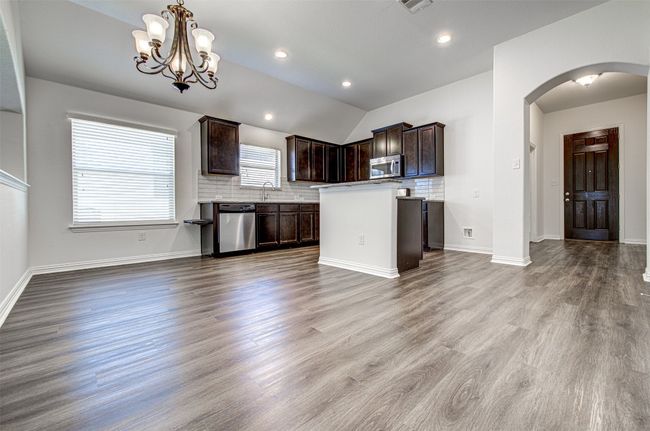 Kitchen with appliances with stainless steel finishes, arched walkways, dark brown cabinets, decorative backsplash, and vaulted ceiling | Image 4