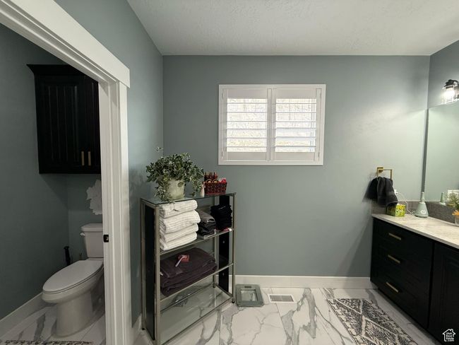 Bathroom featuring toilet, vanity, marble finish floor, baseboards, and visible vents | Image 34