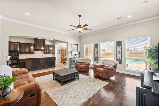 Living room featuring arched walkways, ceiling fan, wood floors, crown molding, and recessed lighting | Image 9