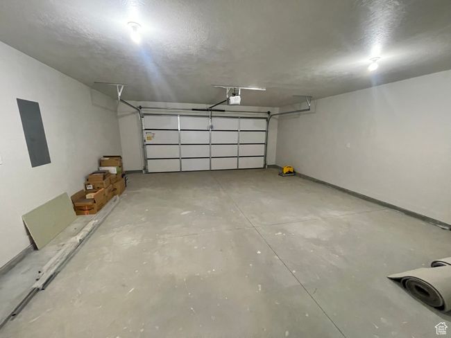 Garage featuring electric panel, a garage door opener, and baseboards | Image 5