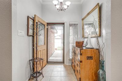 Foyer entrance featuring light tile patterned flooring, crown molding, and a chandelier | Image 3