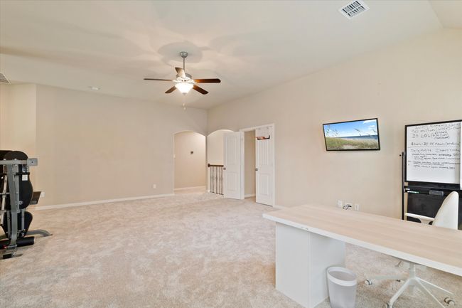 Unfurnished office featuring a ceiling fan, arched walkways, light colored carpet, baseboards, and vaulted ceiling | Image 22