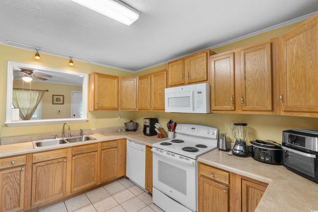 Kitchen featuring white appliances, light tile patterned floors, light countertops, track lighting, and ceiling fan | Image 6