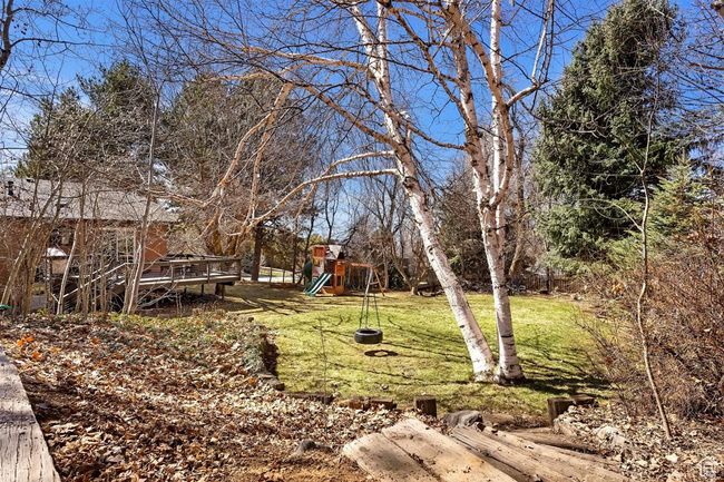 View of grassy yard featuring a playground and a deck | Image 36