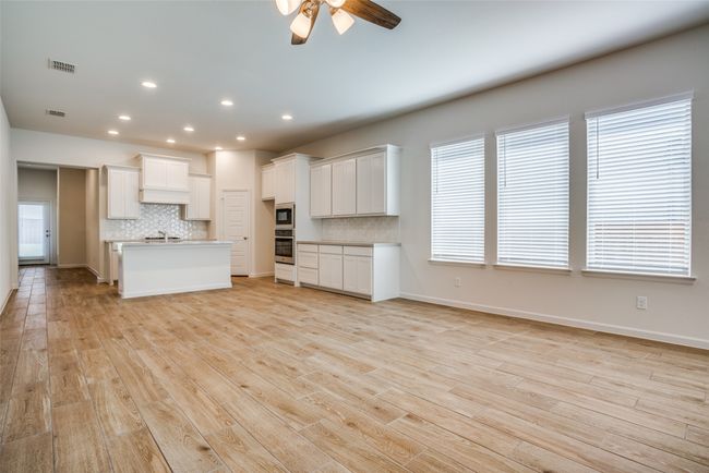 Kitchen featuring oven, built in microwave, decorative backsplash, ceiling fan, and open floor plan | Image 5