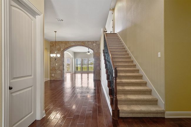 Staircase featuring arched walkways, wood finished floors, and ornate columns | Image 6