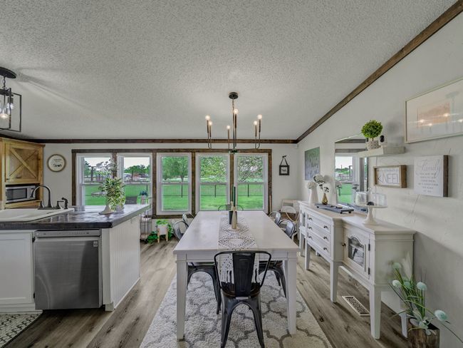 Dining area featuring light wood look floors, plenty of natural light, a chandelier, house two. | Image 25