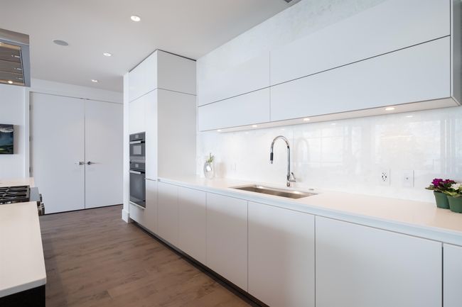 Kitchen with modern cabinets, white cabinets, light countertops, wood finished floors, and recessed lighting | Image 18