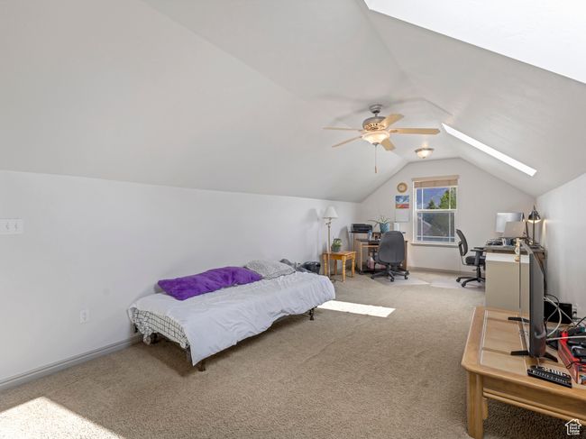 Bedroom with a skylight, lofted ceiling, carpet floors, a desk, and baseboards | Image 26