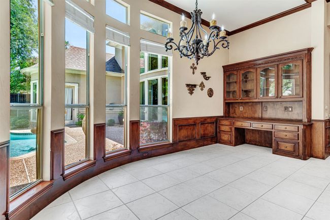 A built-in desk and china cabinet complement the breakfast room with its designer chandelier and large sunny windows. | Image 16