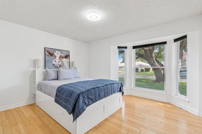Front bedroom with wood flooring, bay window to front yard, and closet with double doors! | Image 21