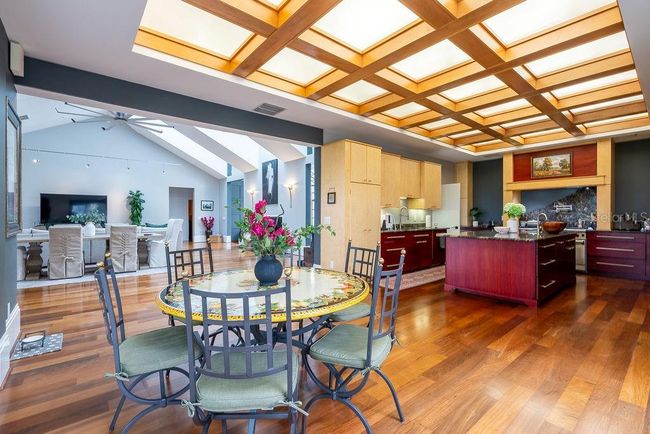The breakfast area, framed by floor-to-ceiling stell windows, showcases captivationg views of the outdoor courtyard, sprawling front lawn dotted with majestic live oaks and the pastures beyond. | Image 21