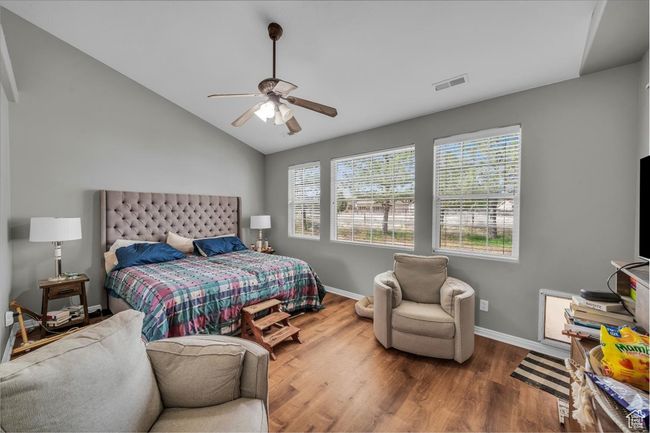 Bedroom featuring lofted ceiling, wood finished floors, visible vents, a ceiling fan, and baseboards | Image 18
