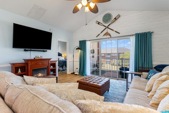 Living room featuring a glass covered fireplace, wood finished floors, high vaulted ceiling, and ceiling fan | Image 5