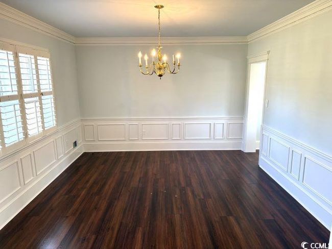 Empty room with dark wood-type flooring, a chandelier, and ornamental molding | Image 9