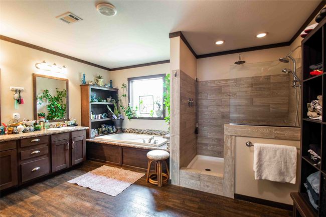 Master Bathroom featuring vanity, a bath, wood finished floors, a walk in shower, and ornamental molding | Image 16