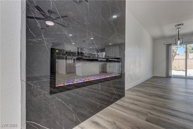 Kitchen with wood finished floors, a textured wall, stainless steel dishwasher, baseboards, and hanging light fixtures | Image 9