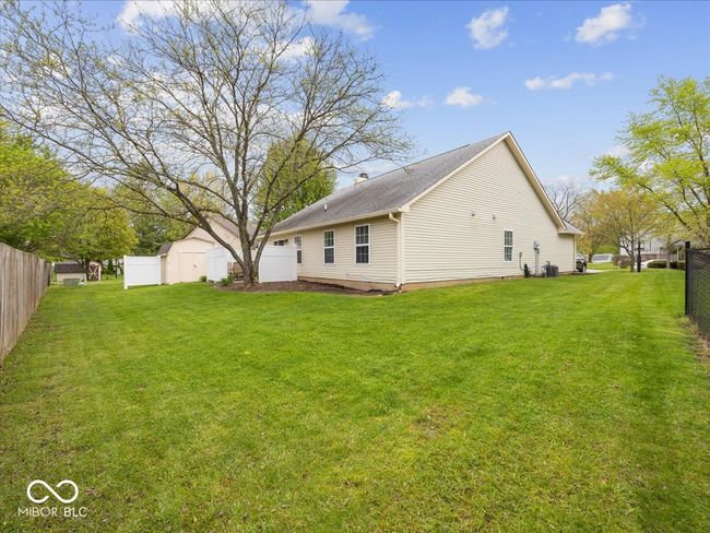 rear view of property with a back patio , storage shed, a lawn, & mature tree. | Image 23