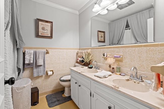 Bathroom with double vanity, ornamental molding, tile patterned floors, tile walls, and wainscoting | Image 22