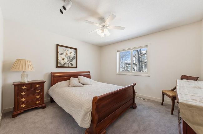 Upper Level Charming 2nd bedroom with a rich wood sleigh bed, matching nightstand, soft carpeting, and a large window providing natural light and private views. | Image 22