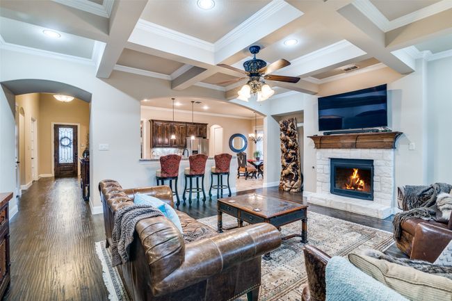 Luxurious open concept living area with coffered ceiling, crown molding, Austin stone fireplace with gas logs. | Image 9