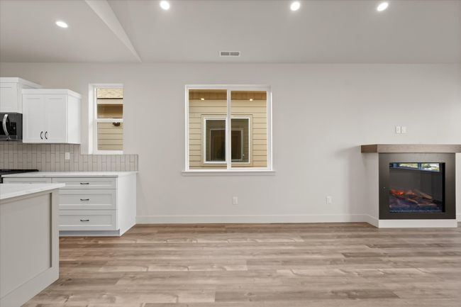 Kitchen with stainless steel microwave, backsplash, white cabinetry, light wood-style floors, and light countertops | Image 10