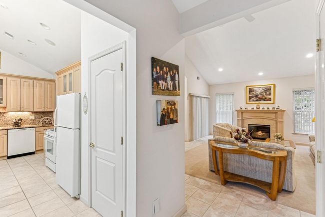 Kitchen with light tile patterned floors, lofted ceiling, and white appliances | Image 12