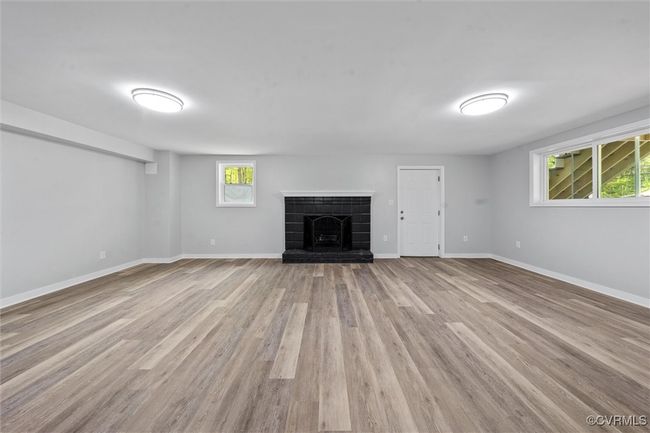 Unfurnished living room featuring a brick fireplace, wood finished floors, and baseboards | Image 24