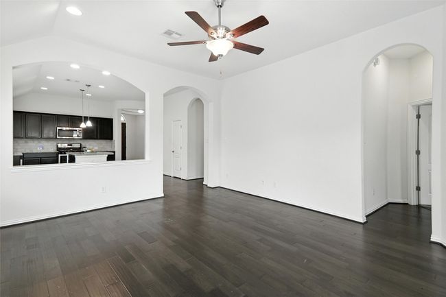 Unfurnished living room with ceiling fan, lofted ceiling, dark wood-style floors, recessed lighting, and arched walkways | Image 23