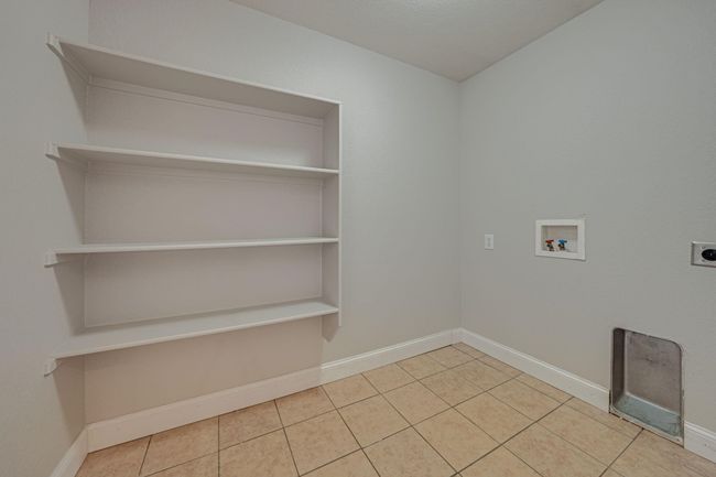 Laundry area featuring hookup for an electric dryer, hookup for a washing machine, and tile patterned floors | Image 10