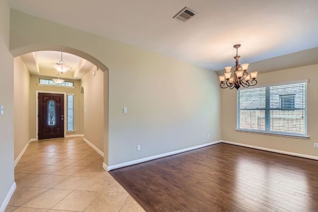 Foyer entrance with a chandelier, arched walkways, light tile patterned floors, and a tray ceiling | Image 6