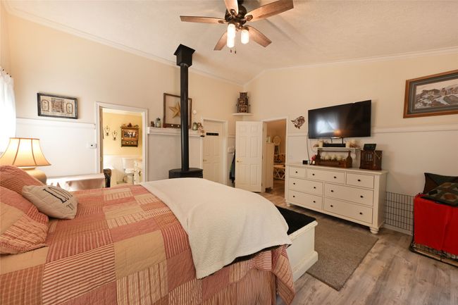 Bedroom with crown molding, vaulted ceiling, wood finished floors, ensuite bath, and a ceiling fan | Image 31