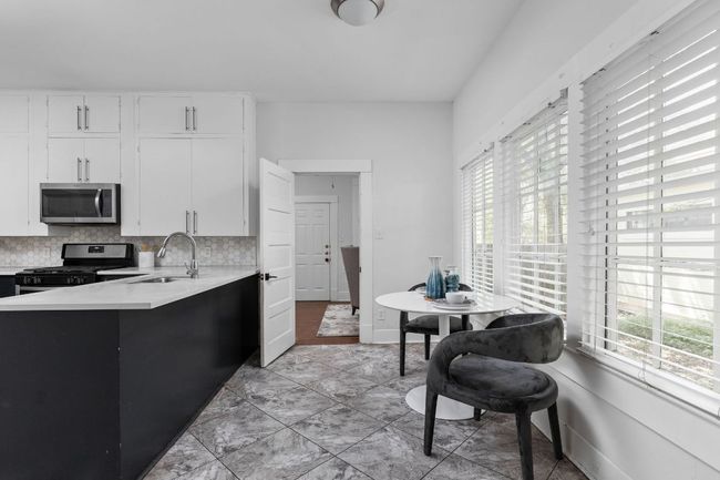 Kitchen with light countertops, appliances with stainless steel finishes, a sink, and backsplash | Image 9