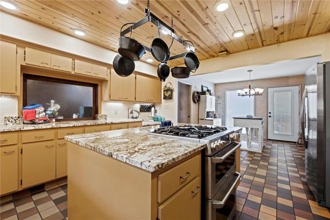 Kitchen featuring stainless steel appliances, wood ceiling, tile patterned floors, a chandelier, and recessed lighting | Image 8