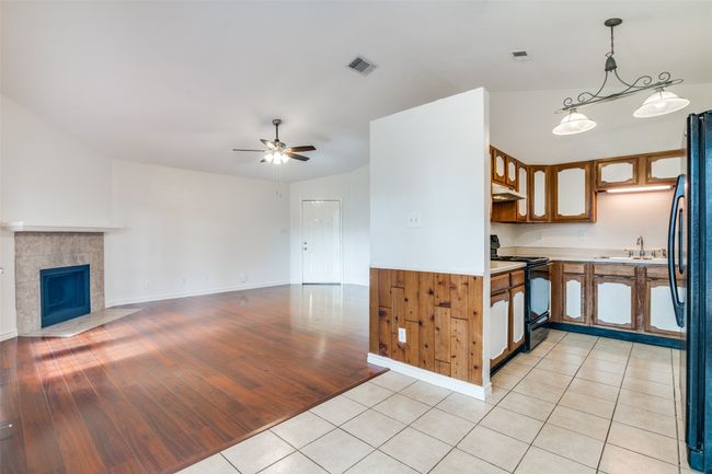 Kitchen with black appliances, under cabinet range hood, light countertops, a ceiling fan, and open floor plan | Image 11