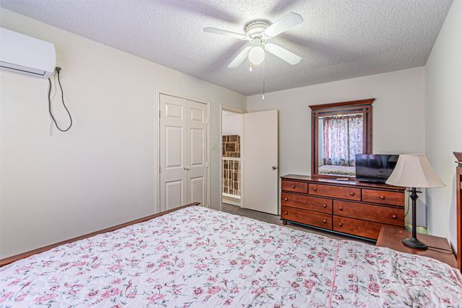 Bedroom featuring an AC wall unit, a textured ceiling, and ceiling fan | Image 22