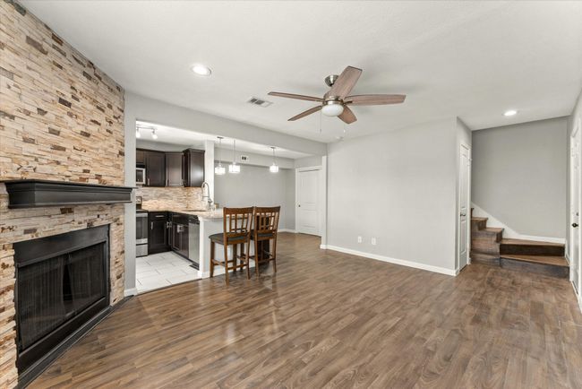Living room with a ceiling fan, stairway, wood finished floors, recessed lighting, and a stone fireplace | Image 8