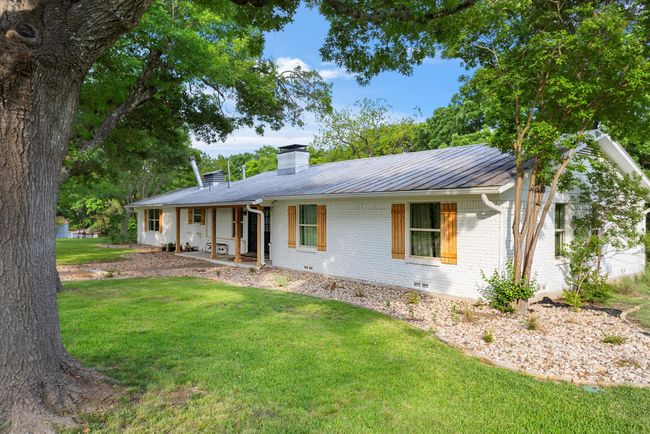 Single story home featuring brick siding, a front yard, a chimney, a standing seam roof, and metal roof | Image 16