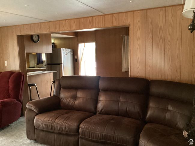 Living area featuring wooden walls and light carpet | Image 5