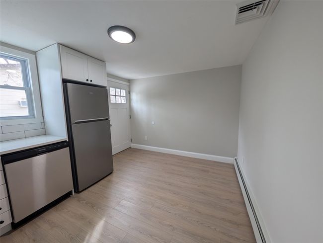 Kitchen with visible vents, stainless steel appliances, light countertops, light wood-style floors, and baseboard heating | Image 19