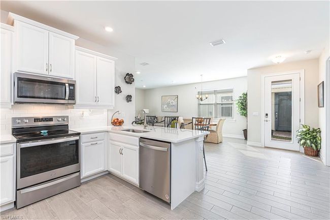 Kitchen with a peninsula, white cabinetry, appliances with stainless steel finishes, and a sink | Image 10