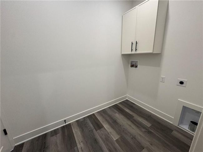 Laundry area featuring dark wood-style flooring, baseboards, cabinet space, electric dryer hookup, and washer hookup | Image 32