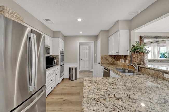 Kitchen with white cabinetry, a sink, appliances with stainless steel finishes, and light stone counters | Image 16