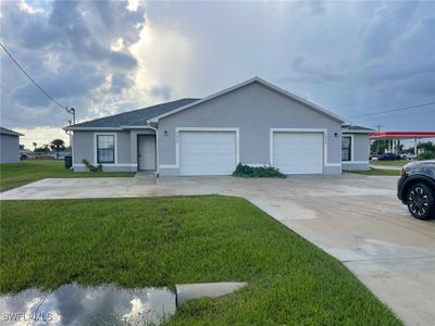 Ranch-style house featuring a garage and a front yard | Image 1