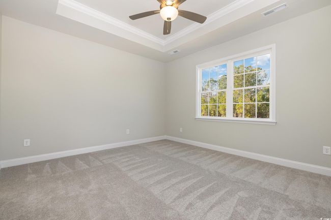 Unfurnished room featuring carpet flooring, ceiling fan, crown molding, and a tray ceiling | Image 15