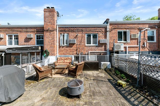 Back of property with a chimney, an outdoor living space with a fire pit, brick siding, a patio, and a cooling unit | Image 19