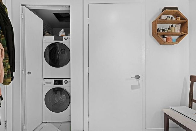 Washroom with light tile patterned floors, stacked washer / dryer, and laundry area | Image 22