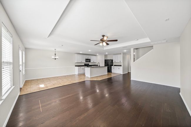 Unfurnished living room featuring a tray ceiling, ceiling fan, a chandelier, wood-type flooring, and recessed lighting | Image 11