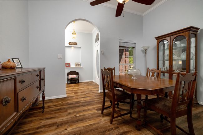 Dining area featuring a ceiling fan, arched walkways, crown molding, and dark wood-style floors | Image 8