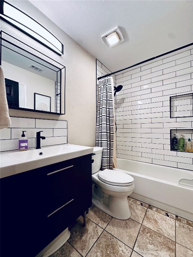 Bathroom with tasteful backsplash, vanity, a textured ceiling, toilet, and shower / bath combo with shower curtain | Image 19